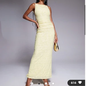Ljusgul långklänning med öppen rygg - Supersnygg ljusgul långklänning från ASOS med smala axelband, öppen rygg och  rosett bak. 🌼Klänningen har en figurnära passform och är gjord i ett blommigt mönstrat tyg. Klänningen är aldrig använd men passar inte mig, det var försent att returnera.