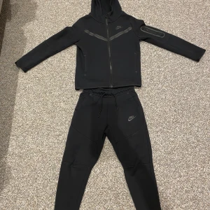 Nike Tech Fleece Set – Svart  - Säljer ett svart Nike Tech Fleece-set i den äldre, populära modellen. Setet består av: 	•	Kofta i storlek M 	•	Byxor i storlek S  Skicket är som nytt – inga defekter, noppor eller slitage. Endast sparsamt använd och alltid väl omhändertagen. Passformen är klassisk för Tech Fleece-serien: snyggt slim men ändå bekväm.                                                    