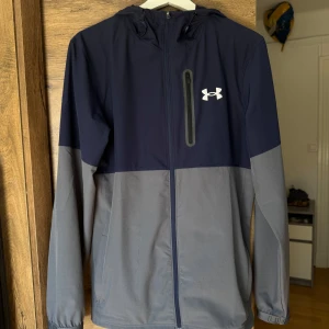 Under Armour vindjacka  - Snygg tvåfärgad vindjacka från Under Armour i marinblått och grått. Nyskick. 