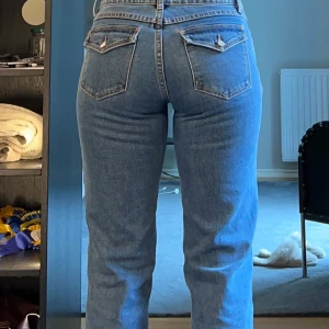 Blå low straight jeans i storlek 26 - Säljer ett par klassiska blå jeans med låg midja och raka ben. Modellen heter A^99 Low Straight och har snygga bakfickor med lock och knapp. Perfekta för dig som gillar en avslappnad men ändå stilren look.