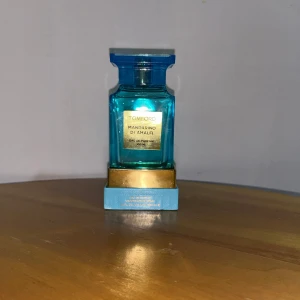 Tom Ford Mandarino di Amalfi parfym - Exklusiv parfym från Tom Ford, Mandarino di Amalfi, i en lyxig blå glasflaska med guldiga detaljer. Flaskan rymmer 100 ml och har en stilren, fyrkantig design. Kommer med matchande blå och guldig förpackning. Doften är fräsch och citrusinspirerad.