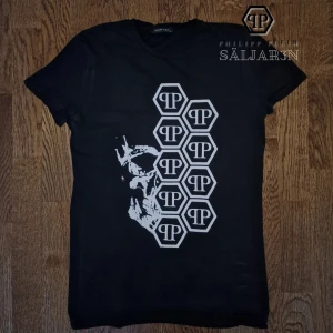 Svart qp T-Shirt - Säljer en exklusiv svart t-shirt i strl S med tryck av vita PP-hexagoner och en integrerad dödskalle – en ikonisk design från märket. Gjord i mjuk, stretchig bomullsblandning för perfekt passform. Endast använd 2 gånger – mycket bra skick. Passar både vardag och kväll, ger en stilren och lyxig look. 📦 Skickas samma dag! Kontakta vid intresse! #Streetwear #Lyxmode #PPStyle #ExklusivtPlagg