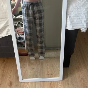 Supersköna pyjamasbyxor - Supermysiga rutiga fleecebyxor från EP Collection i grå och beige toner. Byxorna har normal passform, resår i midjan med snörning och är perfekta för chill dagar hemma. Mjukt och varmt material som känns skönt mot huden.