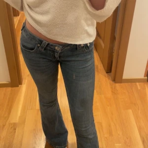 True Religion bootcut jeans blå - Snygga blå jeans från True Religion med bootcut passform och låg midja. Klassiska detaljer som fem fickor, synliga sömmar och ikonisk logga på bakfickan. Perfekta för dig som gillar en avslappnad men trendig stil. Passar dig som är ca 165-167