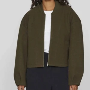 Olivgrön bomberjacka med dragkedja - Snygg olivgrön bomberjacka med klassisk krage och rak passform. Jackan har långa ärmar och stängs med dragkedja framtill. Perfekt för dig som gillar en stilren och enkel look.