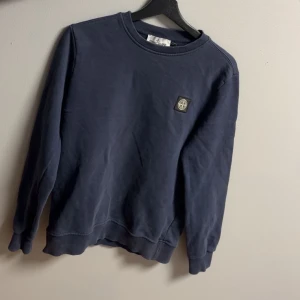 Blå sweatshirt från Stone Island - Säljer en stilren marinblå sweatshirt från Stone Island, den passar perfekt till det mesta enkelt och man kan matcha med mycket! Den är i otroligt bra skick skulle säga 9,5/10! Självklart är den äkta det kan man se på scannen på sista bilden, är det nått man undrar över eller om man vill ha fler bilder är det bara att höra av sig!🤩🙌🏻