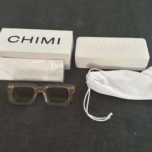 Chimi Ecru fyrkantiga solglasögon - Snygga solglasögon från Chimi i modellen Ecru. De har transparent beige plastbåge med fyrkantig form och mörka linser. Kommer med originalfodral, putsduk och förvaringspåse. Perfekta för dig som vill ha en clean och modern look.