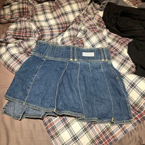 Jeanskjol från Lindex - Snygg blå jeanskjol från Lindex Girls. Kjolen är kort, har markerade sömmar och coola detaljer med dubbla lager. Perfekt för dig som gillar denim och vill ha en trendig look. Midja/32cm, längd/25-28cm. Inte inbyggda shorts🙏