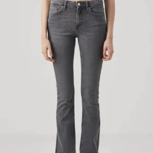 Grå bootcut jeans med medelhög midja  - Snygga grå jeans med bootcut-modell och hög midja. Jeansen har klassisk femficksdesign och är tillverkade i stretchigt denimtyg för en bekväm passform. Perfekta för dig som gillar en tidlös look med lite utsvängda ben. 