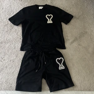 Svarta shorts från AMI Paris med hjärtdetalj - Svarta shorts från AMI Paris med elastisk midja och snörning. Stora broderade hjärtdetaljen med A-logga på ena benet ger en clean och modern vibe. Sköna och lätta, perfekta för sommaren. Materialet är mjukt och känns lyxigt. SHORTSEN ÄR M OCH PASSAR FINT FÖR DEN SOM ÄR 170cm + OCH TRÖJAN ÄR S MEN BAGGY SÅ DEN PASSAR DEN SOM HAR M. PRIS KAN ÄVEN DISKUTERAS