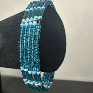 Vintage 90-tals wrap-armband – blå glaspärlor i bohostil -  Färgstarkt wrap-armband från 90-talet i blå glaspärlor på fjädrande minnestråd – sitter snyggt utan lås. Innerdiameter ca 7 cm, bredd ca 1 cm. I fint vintageskick med lätta spår av ålder. Ingen prutning – men jag ger rabatt vid köp av flera saker. Jag rensar både smyckesskrin och garderob, så passa på att kolla mina andra annonser också!  ⸻  