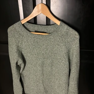 Grå stickad tröja med rund hals - Mysig grå stickad tröja med rund halsringning och långa ärmar. Perfekt för kyliga dagar och enkel att matcha med jeans eller kjol. Tröjan har en klassisk, avslappnad passform och är superbekväm att bära.