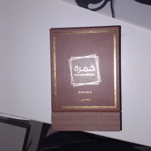 Lattafa Khamrah Qahwa parfym helt tom - Lattafa Khamrah Qahwa parfym i en lyxig brun förpackning med gulddetaljer. Boxen har en elegant design med arabiska och engelska texter. Perfekt för dig som gillar exklusiva dofter och snygg presentation. Helt tom