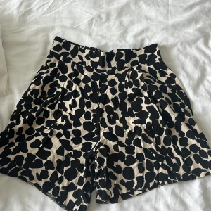 Leopardmönstrade shorts från H&M - Snygga shorts från H&M i beige och svart leopardmönster. Modellen är högmidjad med bred resår i midjan och har praktiska fickor på sidorna. Perfekta för en trendig och chill look under varma dagar.