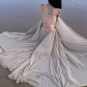 Ljus plisserad långklänning med halterneck - Säljer en ljus, plisserad långklänning med halterneck och smala axelband. Klänningen har ett luftigt fall och är tillverkad i ett tunt, mjukt material som ger en elegant känsla. Perfekt för sommarens tillfällen!