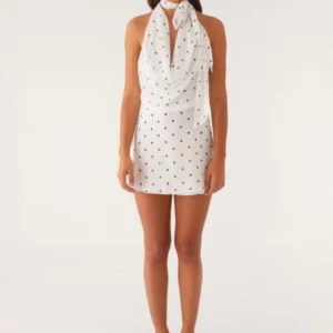 Vit prickig halterneckklänning - Superfin vit kortklänning från peppermayo med svarta prickar och halterneck. Klänningen har en draperad urringning och knyts i nacken. Perfekt för sommarens alla tillfällen!