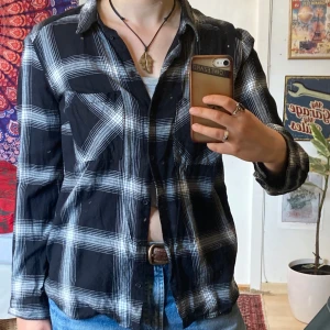 Svartvit rutig skjorta, S/M - Svart och vit rutig skjorta, storlek 42 men liten i storleken så känns som S/M. Sjortan är i mjukt materal, väldigt skön att ha på sig. Nyskick. Använder inte längre, så måste tyvärr sälja.