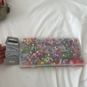 Pärlset med elastisk tråd - Stort kit med färgglada pärlor i olika former och bokstäver, perfekt för att göra egna armband, halsband eller örhängen. Medföljer 10 meter vit elastisk tråd. Pärlorna är i plast och finns i nyanser av rosa, lila, grön, gul, blå och fler färger.