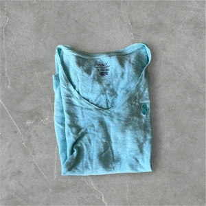 Ljusblå t-shirt från Polo Ralph Lauren - Ljusblå t-shirt med v-ringning från Polo Ralph Lauren. Klassisk design med broderad logga på bröstet. Perfekt för en avslappnad och stilren look.