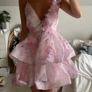 Rosa blommig kortklänning med volang och öppen rygg - Otroligt vacker sommarklänning som är perfekt för alla sommartillfällen, tex bröllop. Aldrig använt, helt ny. Köpte från USA och därmed tullkostnader gör priset högre. 