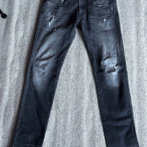 Replay anbass med slitningar - Säljer ett par mörkgråa jeans med snygg shade och diskreta slitningar framtill. Jeansen är mycket bra skick och endast använda ett par gånger. Storleken är w33 och L34. Kan tänka mig gå ner i pris vid snabb affär!