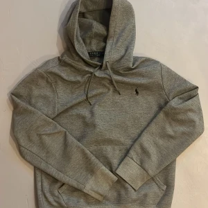 Grå hoodie från Polo Ralph Lauren - Grå hoodie från Ralph Lauren i fint skick! Inga defekter som hål eller fläckar, skick 9/10! Storlek S! Sparsamt använd och passar till sena sommarkvällar lika bra som en tidig vintermorgon ❄️☀️!