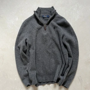 Grå merinoulltröja Polo Ralph Lauren - Mysig grå långärmad tröja från Polo Ralph Lauren i 100% merinoull. Halv dragkedja med läderdetalj och broderad logga på bröstet. Perfekt för lager-på-lager och chill stil under höst och vinter. Storlek M men den är grymt i tvätten så nu är den typ S-XS