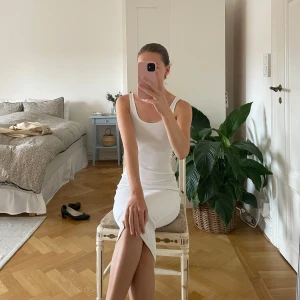 Vit ribbad långklänning - Säljer en stilren vit långklänning med smala axelband och rund halsringning. Klänningen är ribbad och har en tight passform som framhäver siluetten. Perfekt för dig som gillar minimalistisk och fräsch stil.