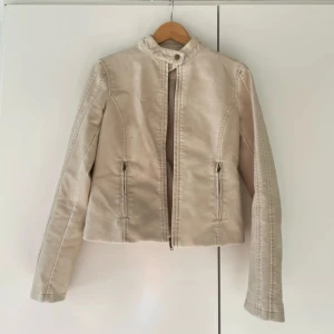 Beige skinnjacka från Reclaimed Vintage - Säljer en beige skinnjacka från Reclaimed Vintage med hög krage och dragkedja framtill. Mycket bra skick 🩷