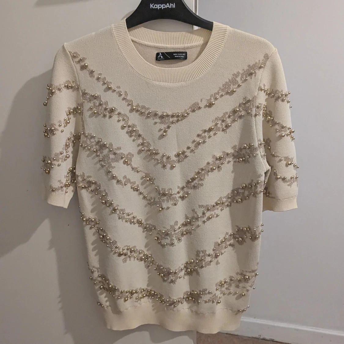 Beige stickad tröja med pärlor och spetsdetaljer