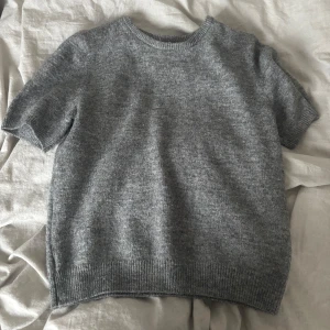 Grå stickad kortärmad tröja - Säljer denna gråa kortärmade stickade tröjan från H&M! Perfekt till svala sommarkvällar!              Säljer den då den aldrig har kommit till andvändning och den har använts endast en gång. Nypris: 150kr🩶