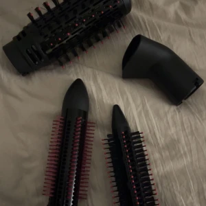 Remington varmluftsborste med tillbehör - Säljer en Remington varmluftsborste med flera utbytbara borsthuvuden och stylingmunstycke. Svart och rosa design, perfekt för att styla och forma håret. Medföljer original förvaringspåse.
