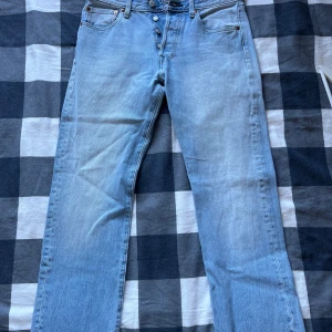 Levis 501 ljusblå jeans - Säljer ett par klassiska Levis 501 jeans i ljusblå tvätt. Byxorna har raka ben, knappgylf och fem fickor. Perfekta för dig som gillar en tidlös och avslappnad stil. Ikonisk Levis-lapp bak i midjan.