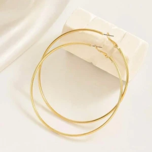 Stora guldiga hoops örhängen - Säljer ett par stora, tunna hoops i guldtonad metall. Perfekta för att ge en statement-look till din outfit. Enkla och stilrena, passar dig som gillar minimalistiska smycken med attityd.