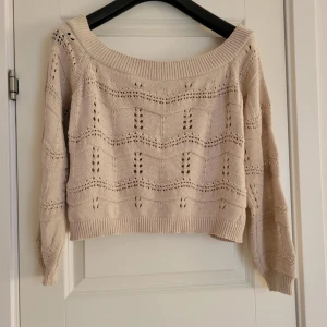 Beige stickad tröja - Säljer en beige stickad tröja med ett vackert hålmönster. Tröjan har en bred halsringning och långa ärmar. Perfekt för en mysig dag.