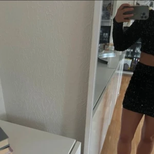 Svart glittrig oneshoulder klänning - Snygg svart klänning med glittriga detaljer och en cool oneshoulder-design. Den har en tight passform och en liten cut-out på sidan som ger en extra edge. Perfekt för en utekväll eller fest! Aldrig använd 