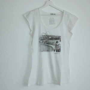 Vit t-shirt med tryck från Esprit - Säljer en vit t-shirt från Esprit med ett svartvitt tryck av ett landskap och en person på ryggen. T-shirten har korta ärmar och en rund halsringning. Perfekt för en avslappnad stil. 🖤