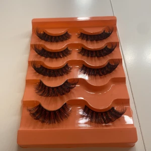 Falska ögonfransar i set - Snygga och fylliga falska ögonfransar i ett set med fem par. Perfekta för att ge dina ögon en dramatisk look. De är placerade i en orange förpackning som gör det enkelt att förvara och använda dem.