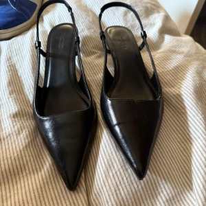 Svarta slingbacks med spetsig tå - Snygga svarta pumps med spetsig tå och smal klack.  Klack höjd på ca 2/3 cm. Aldrig använda, endast testade men hade för breda fötter för dessa, därav säljer jag dom