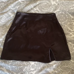 Svart satinkjol med slits  - Jättefin svart satinkjol med dragkedja och slits på sidan. Storlek S men passar XXS om man vill ha den lite mer lowwaist. Har även en champagne-färgad i strl M