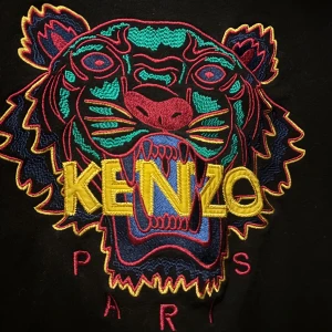 Kenzo tröja - Säljer en svart tröja från Kenzo med ett färgglatt tigerbroderi på framsidan. Tröjan har långa ärmar och en rund halsringning. Perfekt för dig som vill ha en statement piece i garderoben!
