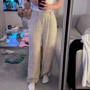 Beige linnebyxor från Gina Tricot - Snygga beige linnebyxor från Gina Tricot i storlek S. Byxorna har en högmidjad passform och vida ben, är tyvärr lite stora för mig! Perfekta för varmare dagar med sitt lätta och luftiga material, upplevs inte genomskinliga!