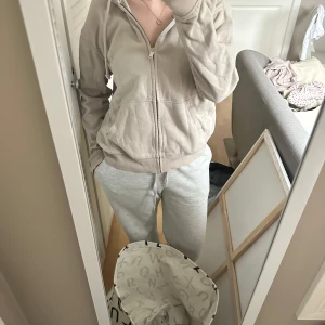 Beige hoodie med dragkedja - Säljer en bekväm beige hoodie med dragkedja framtill. Perfekt för en avslappnad stil. Den har långa ärmar och en huva med snören. Passar bra till vardags och är lätt att matcha med andra plagg.