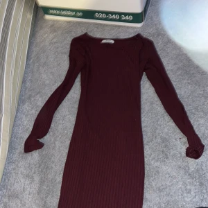 Vinröd ribbad klänning från Bershka - Säljer en stilren vinröd klänning från Bershka i storlek XS. Klänningen är ribbad och har långa ärmar, perfekt för en elegant look. Passar utmärkt till både vardag och festliga tillfällen. 💃