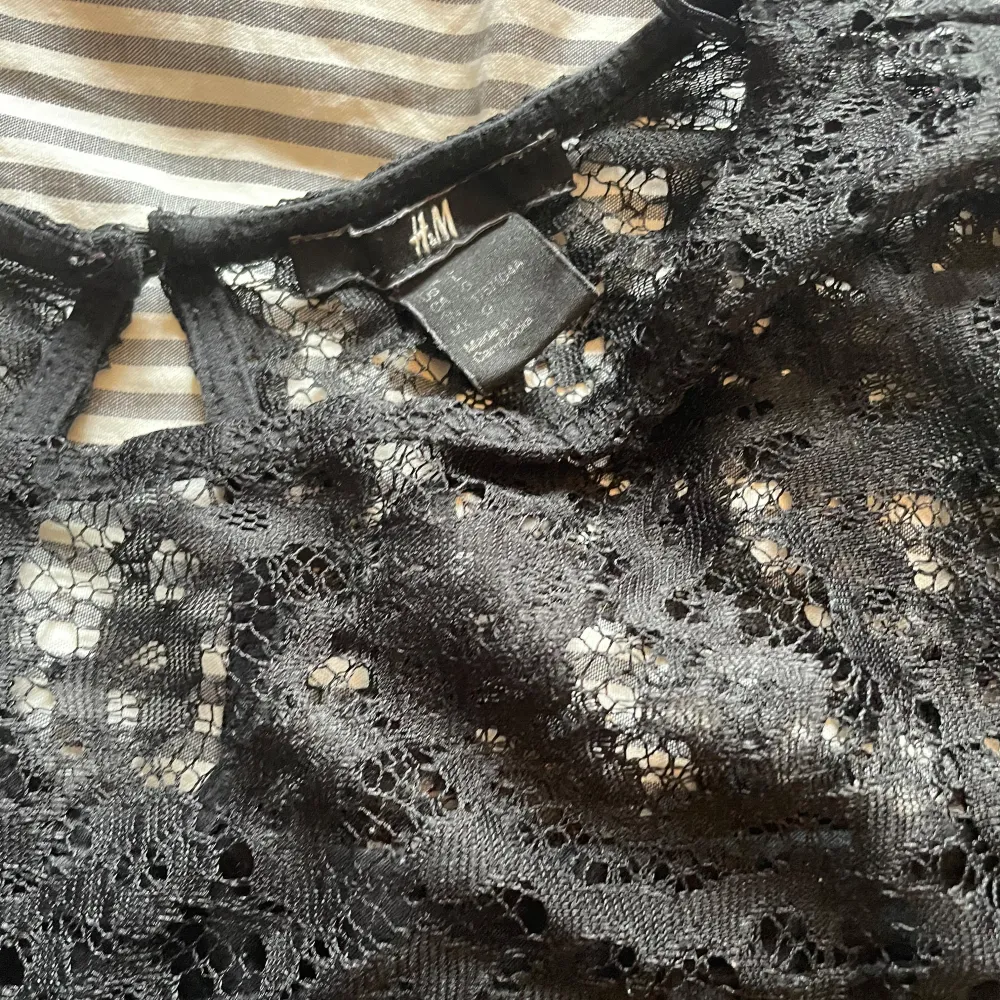 Snygg svart blus från H&M med spetsdetaljer upptill. Blusen har korta ärmar och en elegant design som passar perfekt för en stilren look. Perfekt för att klä upp en vardagsoutfit eller för en kväll ute.. Yläosat.