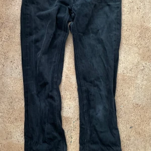 Svarta jeansbyxor från Acne Jeans - Snygga svarta jeansbyxor från Acne Jeans med klassisk design. Byxorna har en dragkedja och knapp framtill samt fickor både fram och bak. Perfekta för en stilren look.