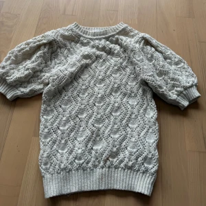 Virkad tröja Zara - Säljer en söt vit stickad tröja från Zara med ett vackert spetsmönster. Tröjan har trekvartsärmar och ribbade kanter vid ärmslut och nederkant. Perfekt för vår och sommar!🤍