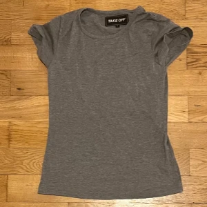 Grå t-shirt från Take Off - Säljer en stilren grå t-shirt från Take Off. Den har en rund halsringning och korta ärmar, perfekt för en avslappnad look. Passar bra till jeans eller shorts. Skicka ett meddelande vid intresse!