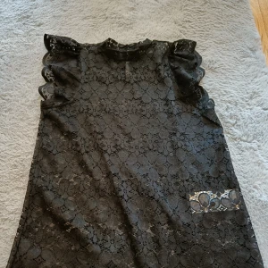 Svart spetsblus från JDY - Snygg svart spetsbmus från JDY i storlek XS. Blusen  har volangdetaljer vid ärmarna och ett vackert blommigt spetsmönster. Perfekt för en elegant look med knappar i ryggen för enkel påklädning. Den är aldrig använd och har haft lappen på som ni kan se på inlägget jag la ut för ett tag sen på den här blusen. Men den har tvättas så lappen är inte på längre. Men den är som sagt aldrig använd.