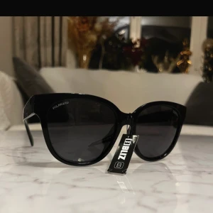 Svarta solglasögon från Bliz - Snygga svarta solglasögon från Bliz med en klassisk design. De har en elegant och stilren look med mörka glas som ger ett sofistikerat intryck. Perfekta för soliga dagar och att matcha med olika outfits.